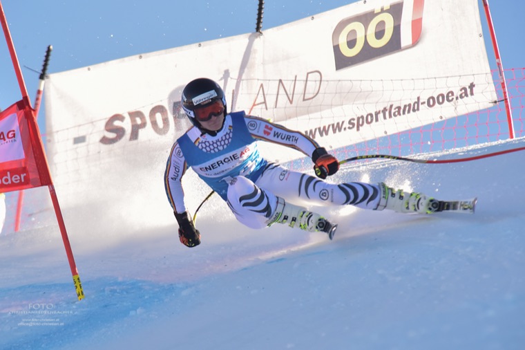 Super-G turn in front of a sponsor banner