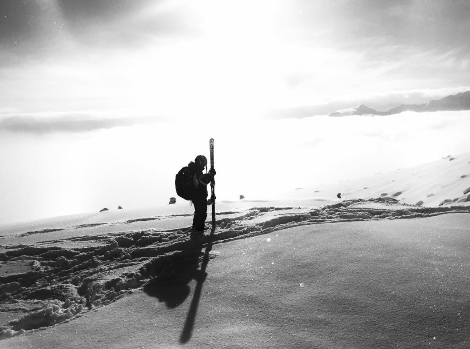 A skier carrying skis on a high alpine ridge